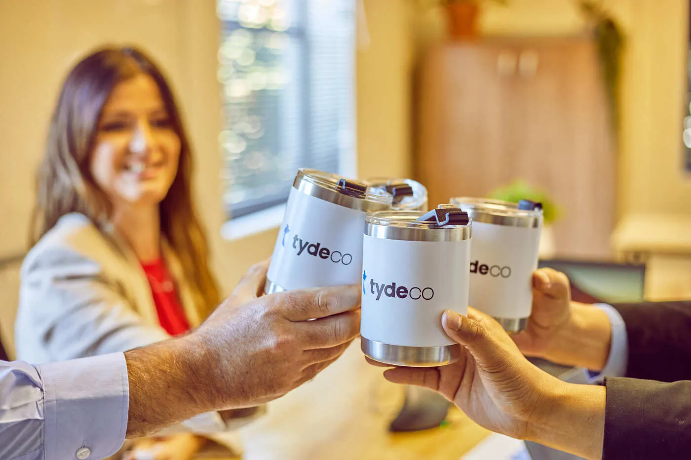 staff members holding cups with Tydeco logo on the cups.