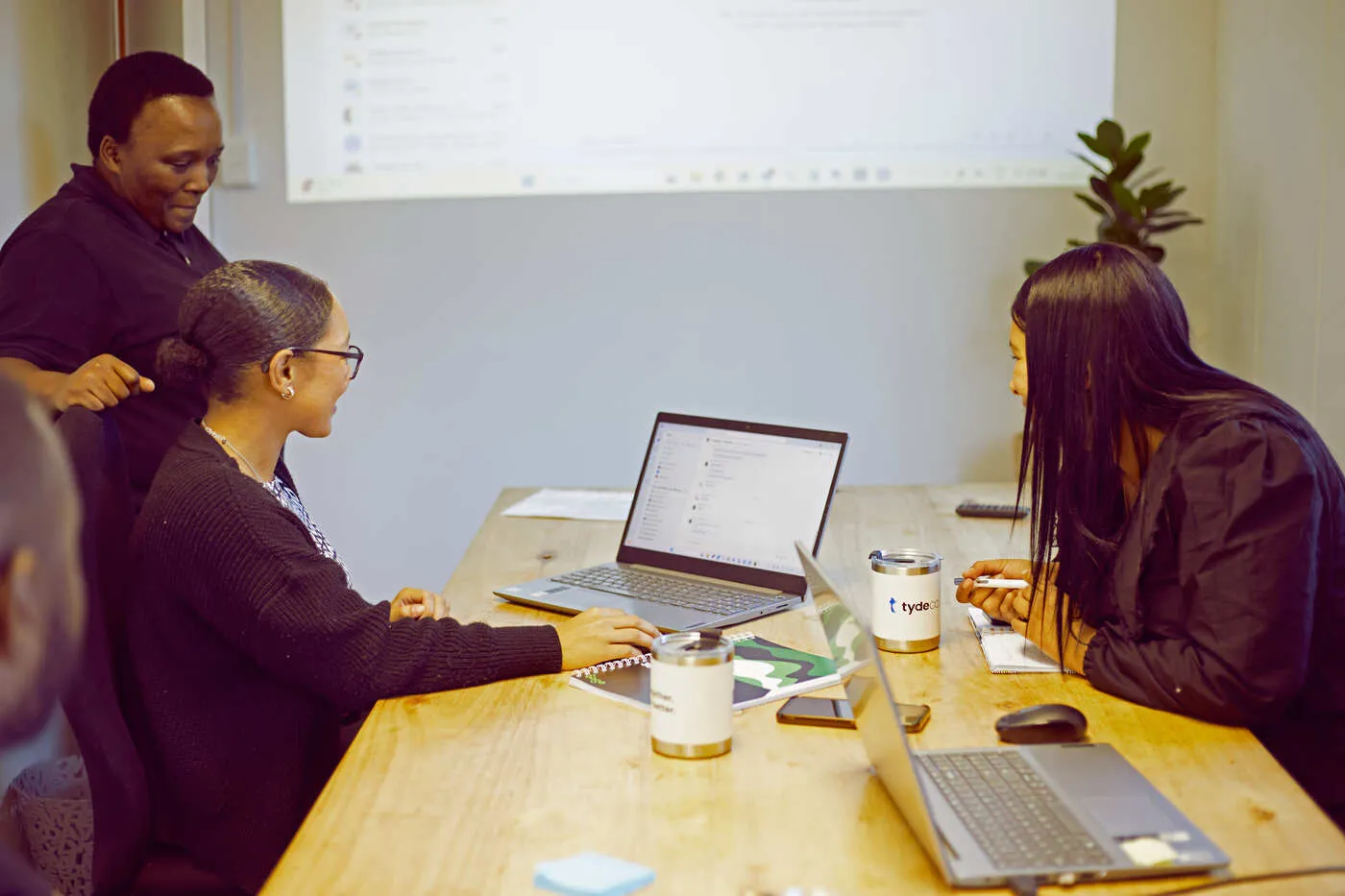 three woman in a meeting all looking at a laptop screen
