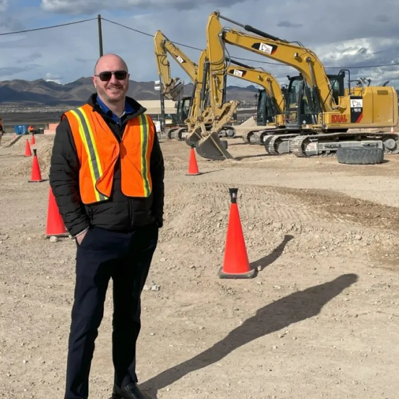 Image of Matt standing with diggers in the background