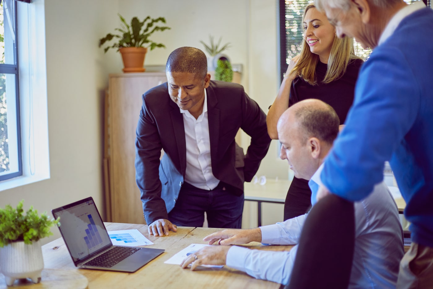 staff members having a meeting gathered around a laptop