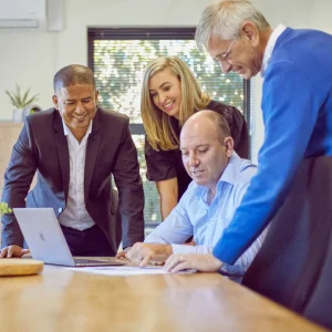 staff members have a meeting gathered around a laptop