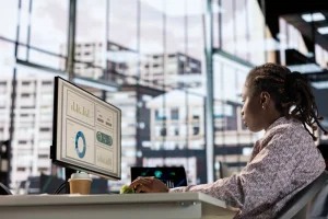IT specialist wearing a headset monitoring data systems on a digital tablet inside a high-tech server room.