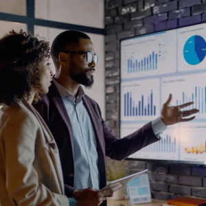 Business professionals presenting and reviewing financial performance data on a digital dashboard.