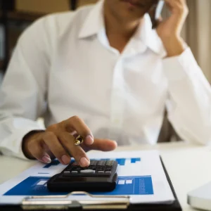 Lawyer struggling to manage financial reports and calculations while speaking on the phone.